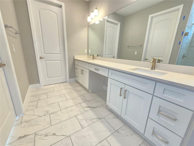 bathroom with double vanity, marble finish floor, baseboards, and a sink