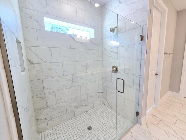 bathroom with marble finish floor, a stall shower, and baseboards