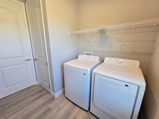 washroom featuring laundry area, light wood-style flooring, baseboards, and separate washer and dryer