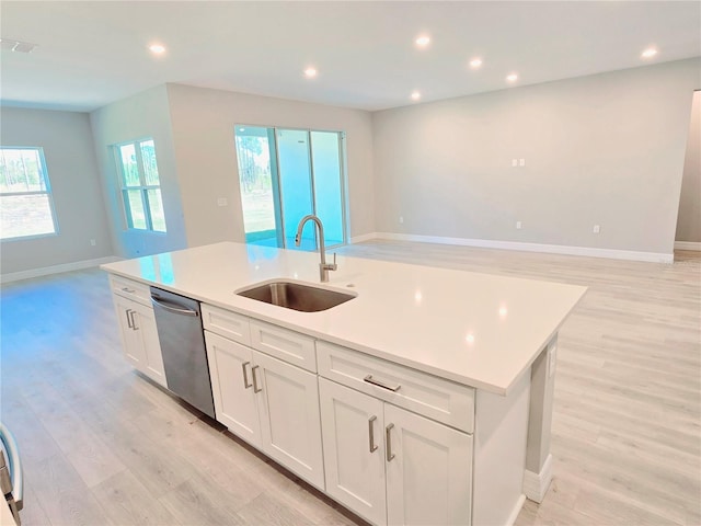 kitchen with recessed lighting, stainless steel dishwasher, open floor plan, a sink, and light wood-type flooring