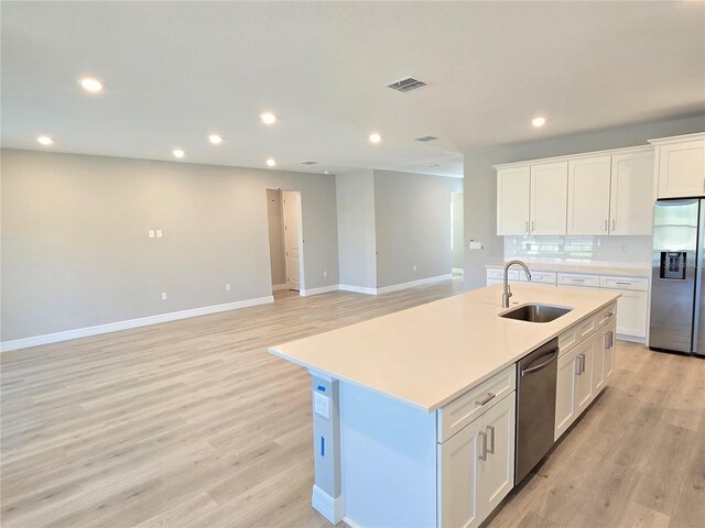 kitchen with a center island with sink, white cabinets, stainless steel appliances, light countertops, and a sink