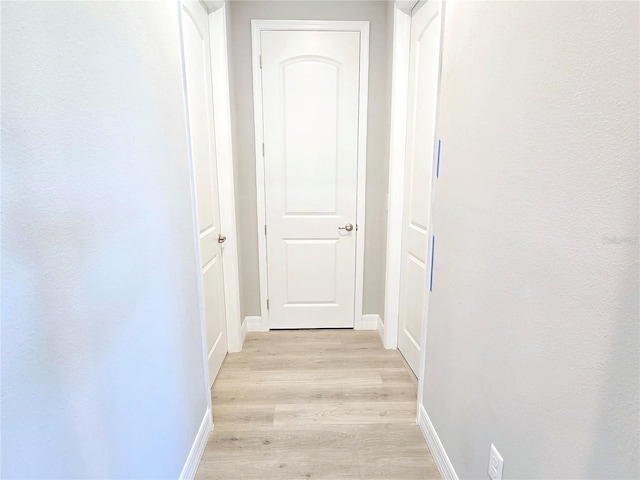 hall with light wood-style flooring and baseboards