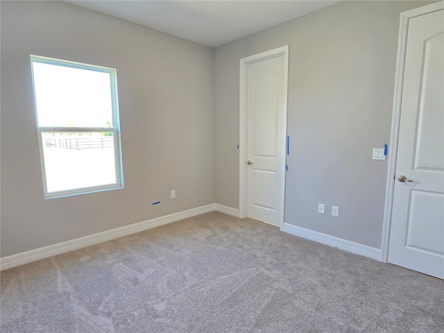 unfurnished room with light carpet and baseboards