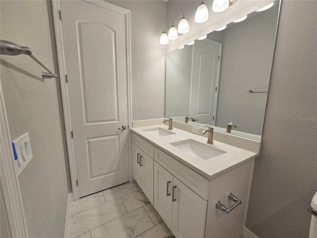 full bath with marble finish floor, double vanity, and a sink