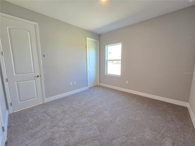 unfurnished room featuring carpet floors and baseboards