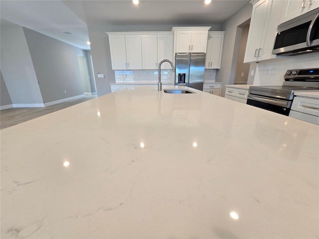 kitchen with white cabinets, tasteful backsplash, stainless steel appliances, and a sink