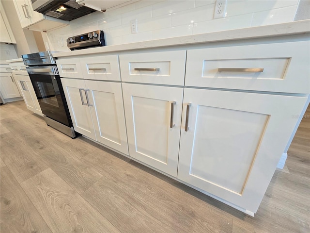 kitchen featuring electric stove, light countertops, light wood-style flooring, decorative backsplash, and white cabinetry