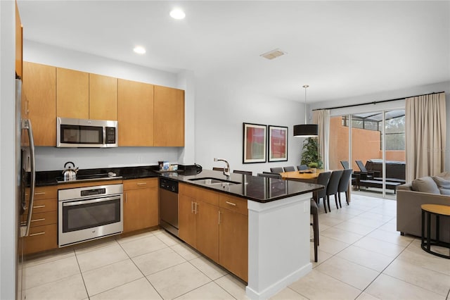 kitchen with open floor plan, decorative light fixtures, a peninsula, stainless steel appliances, and a sink