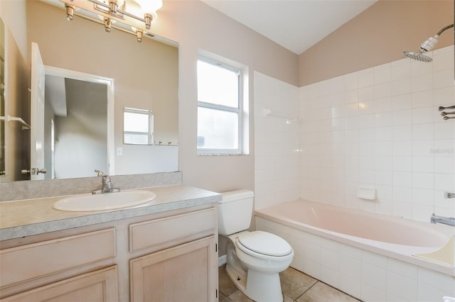 bathroom featuring tiled shower / bath, toilet, vaulted ceiling, vanity, and tile patterned flooring