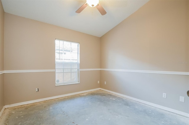 empty room with lofted ceiling, concrete floors, baseboards, and a ceiling fan