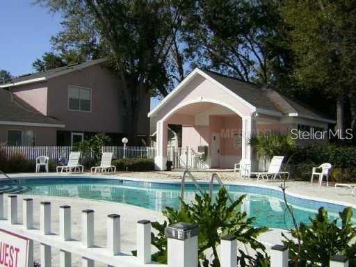 community pool with a patio area and fence