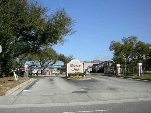 view of street featuring a gate, a gated entry, and curbs