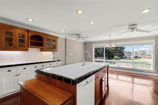 kitchen featuring crown molding, tile counters, backsplash, white dishwasher, and a sink