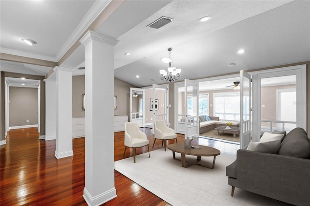 living room featuring lofted ceiling, visible vents, decorative columns, and wood finished floors