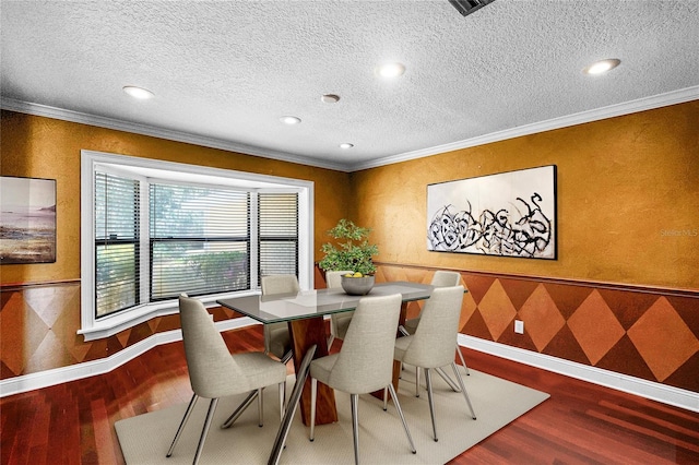 dining room featuring a textured ceiling, baseboards, crown molding, and wood finished floors