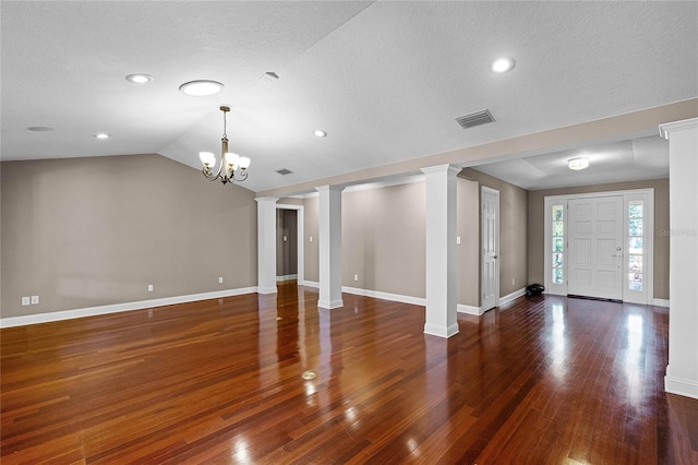 foyer entrance featuring decorative columns, baseboards, visible vents, wood finished floors, and vaulted ceiling