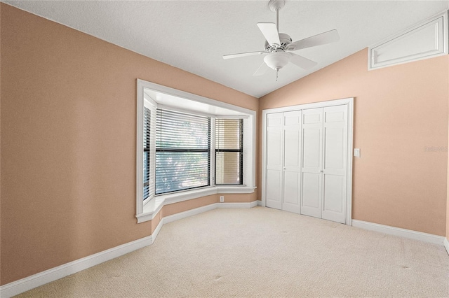 unfurnished bedroom featuring carpet, baseboards, vaulted ceiling, and a closet