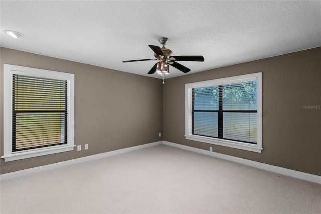 unfurnished room featuring carpet floors, a textured ceiling, baseboards, and a ceiling fan