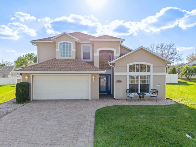 view of front facade featuring a shingled roof, decorative driveway, a front lawn, and stucco siding