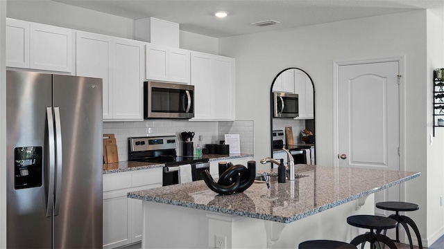 kitchen featuring an island with sink, white cabinetry, and stainless steel appliances