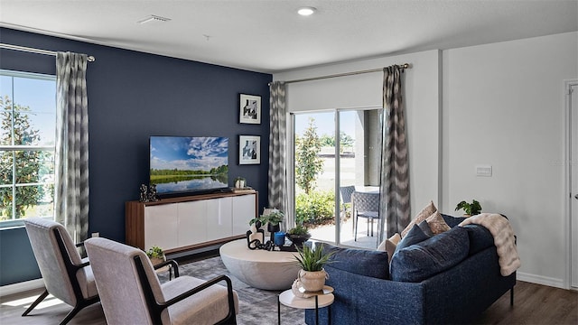 living area with baseboards, plenty of natural light, visible vents, and wood finished floors