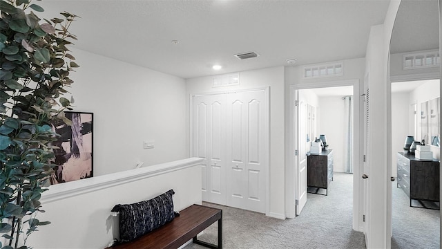 hall featuring visible vents and carpet flooring