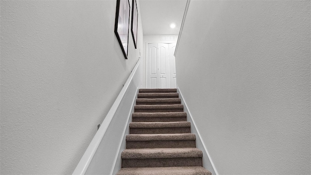 stairs featuring a textured wall and baseboards