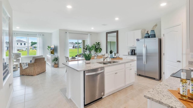 kitchen featuring stainless steel appliances, white cabinets, a kitchen island with sink, and a sink