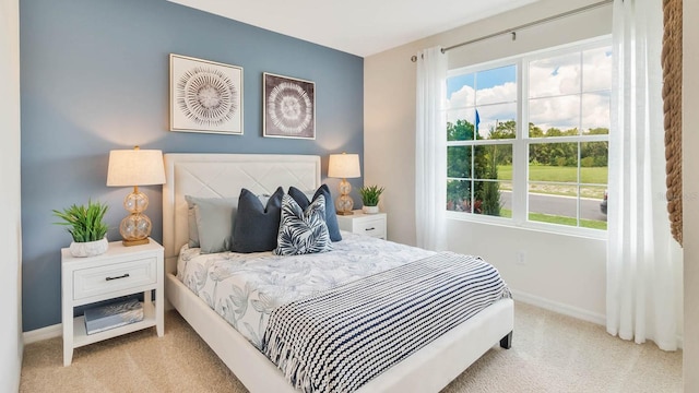 bedroom with baseboards and light colored carpet