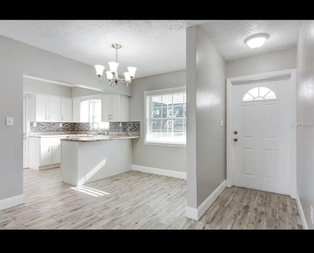 foyer with a textured ceiling, an inviting chandelier, and light wood-style floors