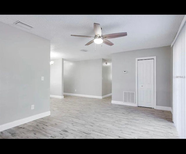 unfurnished room with a ceiling fan, light wood-style flooring, visible vents, and a textured ceiling