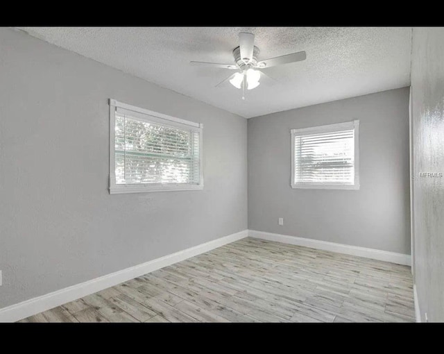 unfurnished room with a textured ceiling, ceiling fan, light wood-style flooring, and baseboards