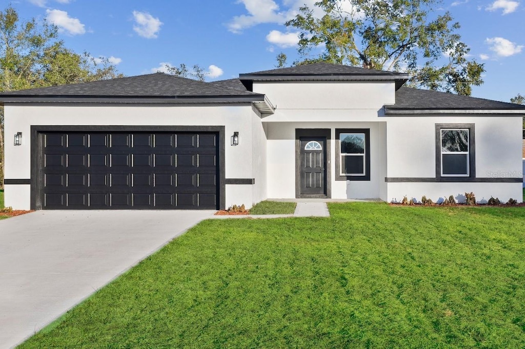 13592 SW 43rd Cir, Ocala, FL 34473 - view of front of home featuring a garage, concrete driveway, a front lawn, and stucco siding