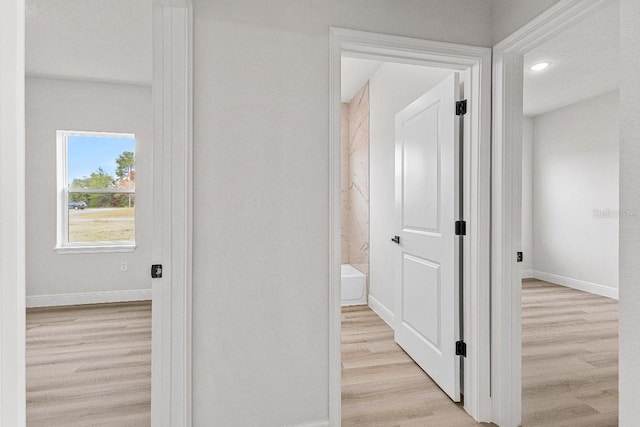 hall with light wood-style floors and baseboards