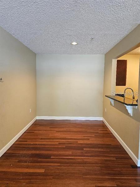 2019 Dixie Belle Dr Unit 2019O, Orlando, FL 32812 - spare room featuring a textured ceiling, baseboards, and wood finished floors