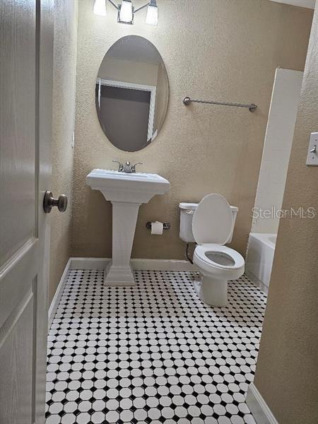2019 Dixie Belle Dr Unit 2019O, Orlando, FL 32812 - bathroom featuring a textured wall, tile patterned floors, toilet, and baseboards