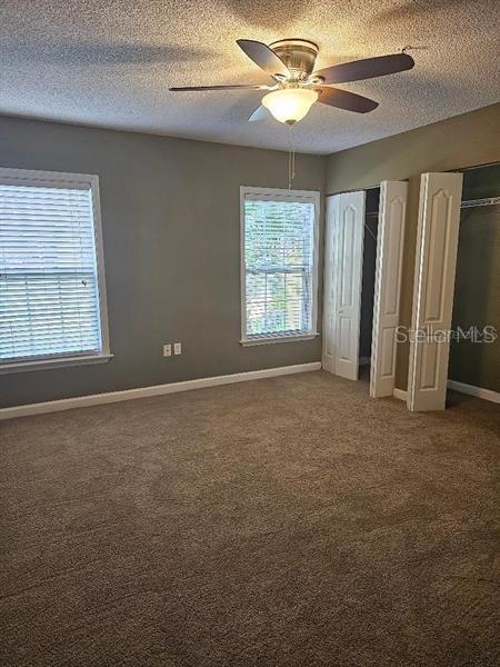 2019 Dixie Belle Dr Unit 2019O, Orlando, FL 32812 - unfurnished bedroom with ceiling fan, a textured ceiling, baseboards, multiple closets, and carpet
