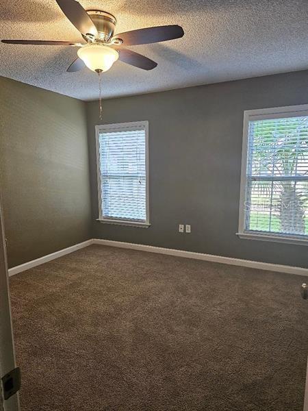 2019 Dixie Belle Dr Unit 2019O, Orlando, FL 32812 - unfurnished room featuring a ceiling fan, carpet, a textured ceiling, and baseboards