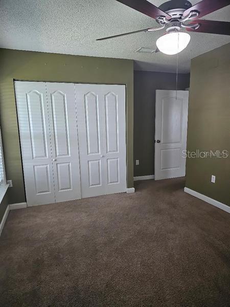 2019 Dixie Belle Dr Unit 2019O, Orlando, FL 32812 - unfurnished bedroom with baseboards, ceiling fan, a textured ceiling, carpet floors, and a closet