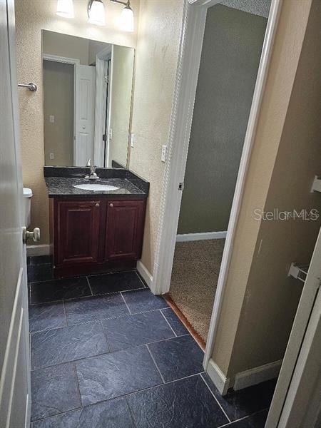 2019 Dixie Belle Dr Unit 2019O, Orlando, FL 32812 - bathroom featuring baseboards, a textured wall, vanity, and stone tile floors