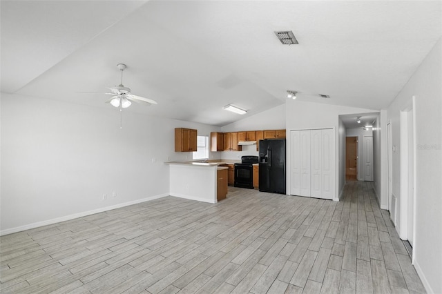 kitchen featuring visible vents, brown cabinetry, open floor plan, under cabinet range hood, and black appliances