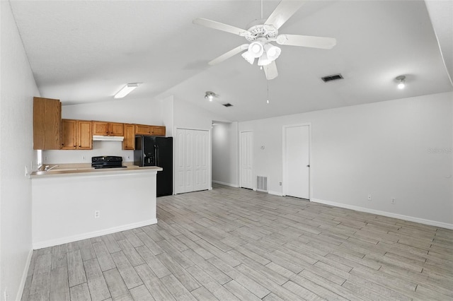 kitchen featuring visible vents, light wood-style floors, brown cabinets, under cabinet range hood, and black appliances