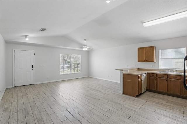 kitchen featuring visible vents, brown cabinetry, dishwasher, light wood-style flooring, and a peninsula