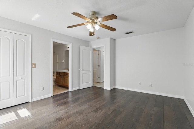 unfurnished bedroom featuring dark wood-style floors, baseboards, visible vents, and a closet