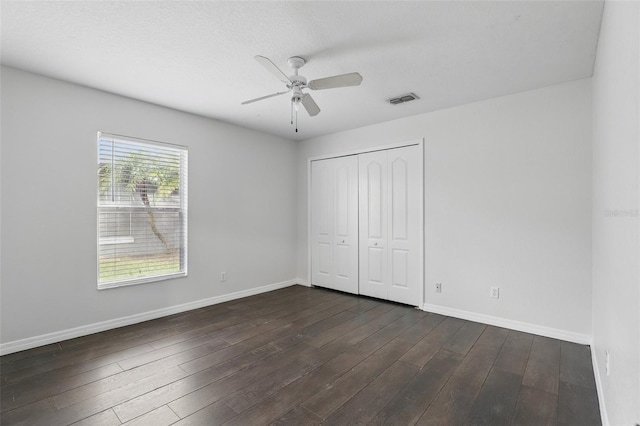 unfurnished bedroom featuring a closet, dark wood finished floors, visible vents, and baseboards