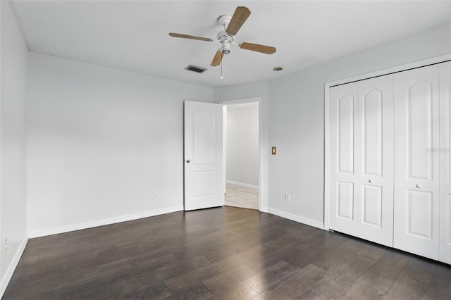 unfurnished bedroom featuring a ceiling fan, visible vents, baseboards, a closet, and dark wood finished floors