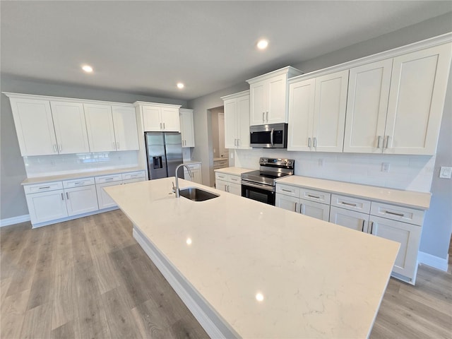 kitchen with light wood-style flooring, stainless steel appliances, a spacious island, a sink, and white cabinets