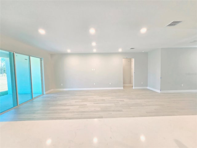 spare room with baseboards, light wood-type flooring, visible vents, and recessed lighting