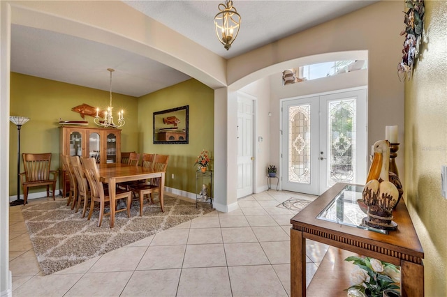 entryway with baseboards, arched walkways, an inviting chandelier, french doors, and light tile patterned flooring