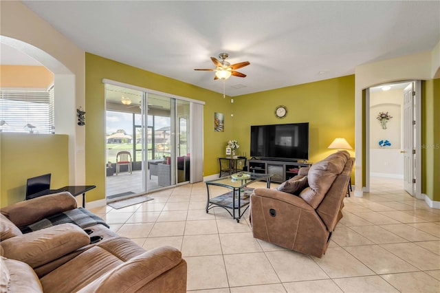 living area with light tile patterned floors, a ceiling fan, and baseboards